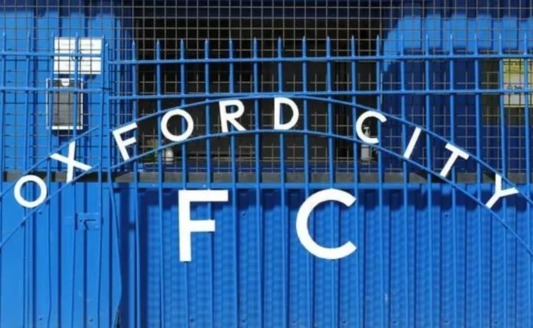 Cổng chính sân vận động Court Place Farm của Oxford City FC, biểu tượng của sự hiện đại 'sơ khai' ở bóng đá bán chuyên Anh