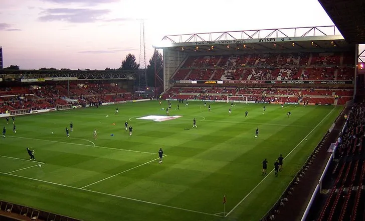 Góc nhìn từ khán đài bên trong sân The City Ground, cho thấy sân cỏ và các khán đài đối diện