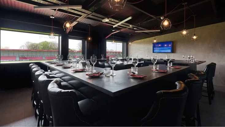 Không gian bên trong phòng tiếp khách (hospitality suite) tại Peninsula Stadium, được trang trí đơn giản nhưng ấm cúng, cho thấy Salford City FC vẫn nỗ lực mang đến trải nghiệm đặc biệt cho khách VIP dù không thể sánh bằng những 'ông lớn' như Old Trafford hay Etihad.