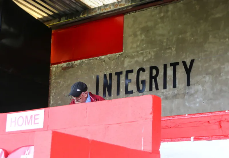Một cổ động viên Salford City FC với khăn quàng cổ màu đỏ trắng truyền thống, gương mặt hân hoan trước trận đấu, thể hiện niềm đam mê cháy bỏng với đội bóng 'con cưng' của những huyền thoại Manchester United.