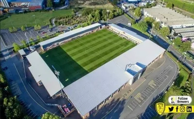 Toàn cảnh Pirelli Stadium nhìn từ trên cao, sân nhà của Burton Albion FC với mái che màu trắng nổi bật giữa khu dân dân
